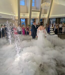 Eleganckie nakrycie stołu weselnego a w tle saksofonistka na żywo, symbolizująca współpracę muzyki z kuchnią.